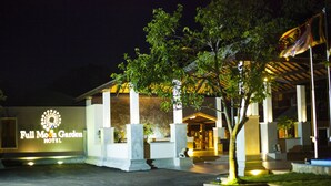 Exterior del Hotel Full Moon Garden, con un llamativo letrero iluminado, un acceso cubierto y un jardín bien iluminado.