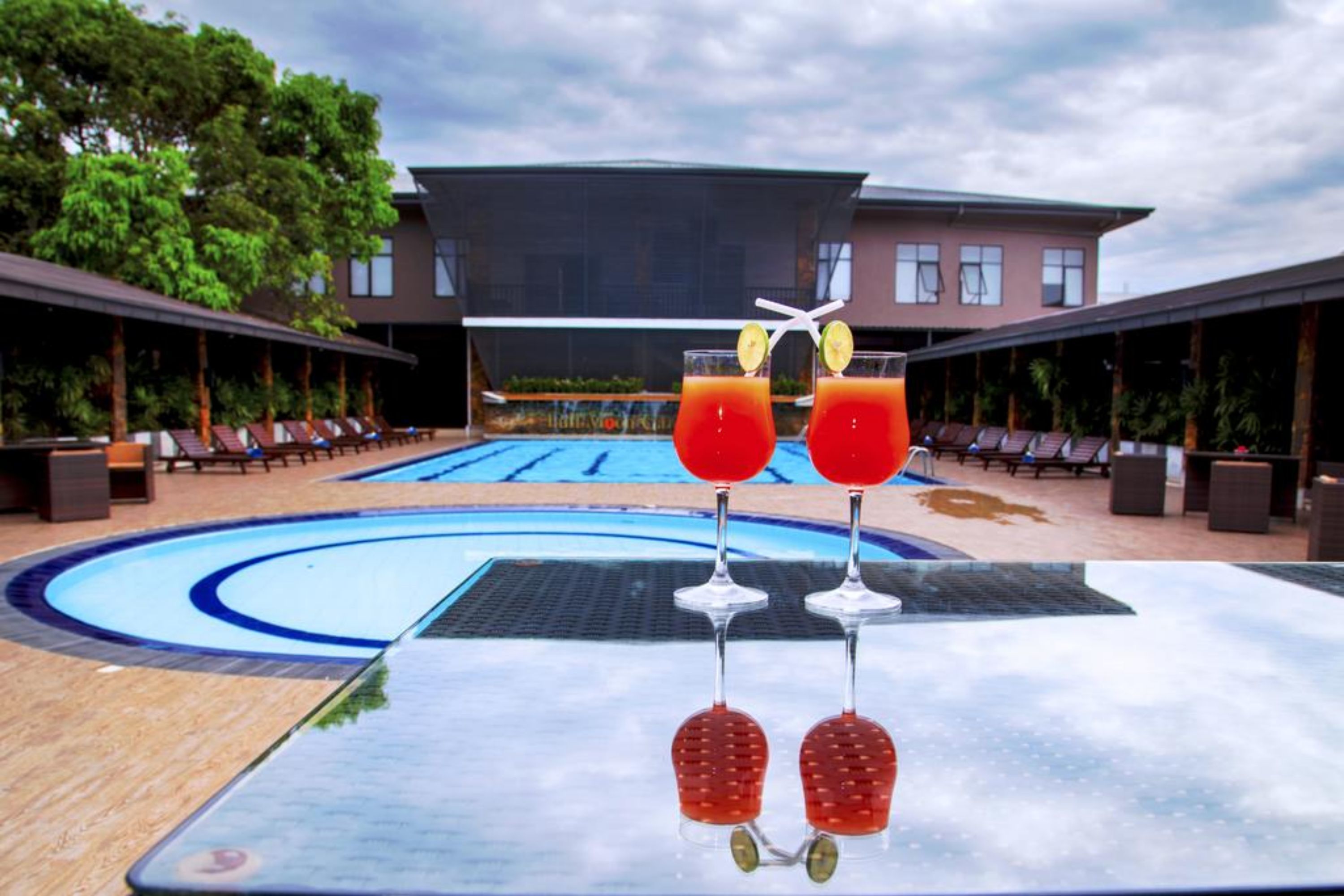 A poolside area with lounge chairs and a building in the background.