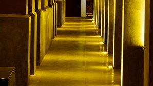 Un pasillo con columnas regularmente distribuidas y una iluminación uniforme a lo largo de las paredes.