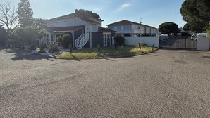 En boligejendom med indkørsel, en port med låge og et toetages hus med en overdækket veranda.