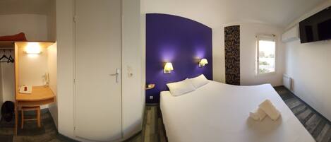 Een hotelkamer met een bed, een bureau, een stoel, een kledingkast en een badkamer.