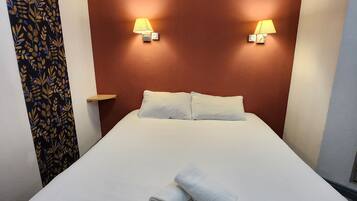 Una habitación de hotel con una cama grande, dos lámparas de noche y una cortina estampada.