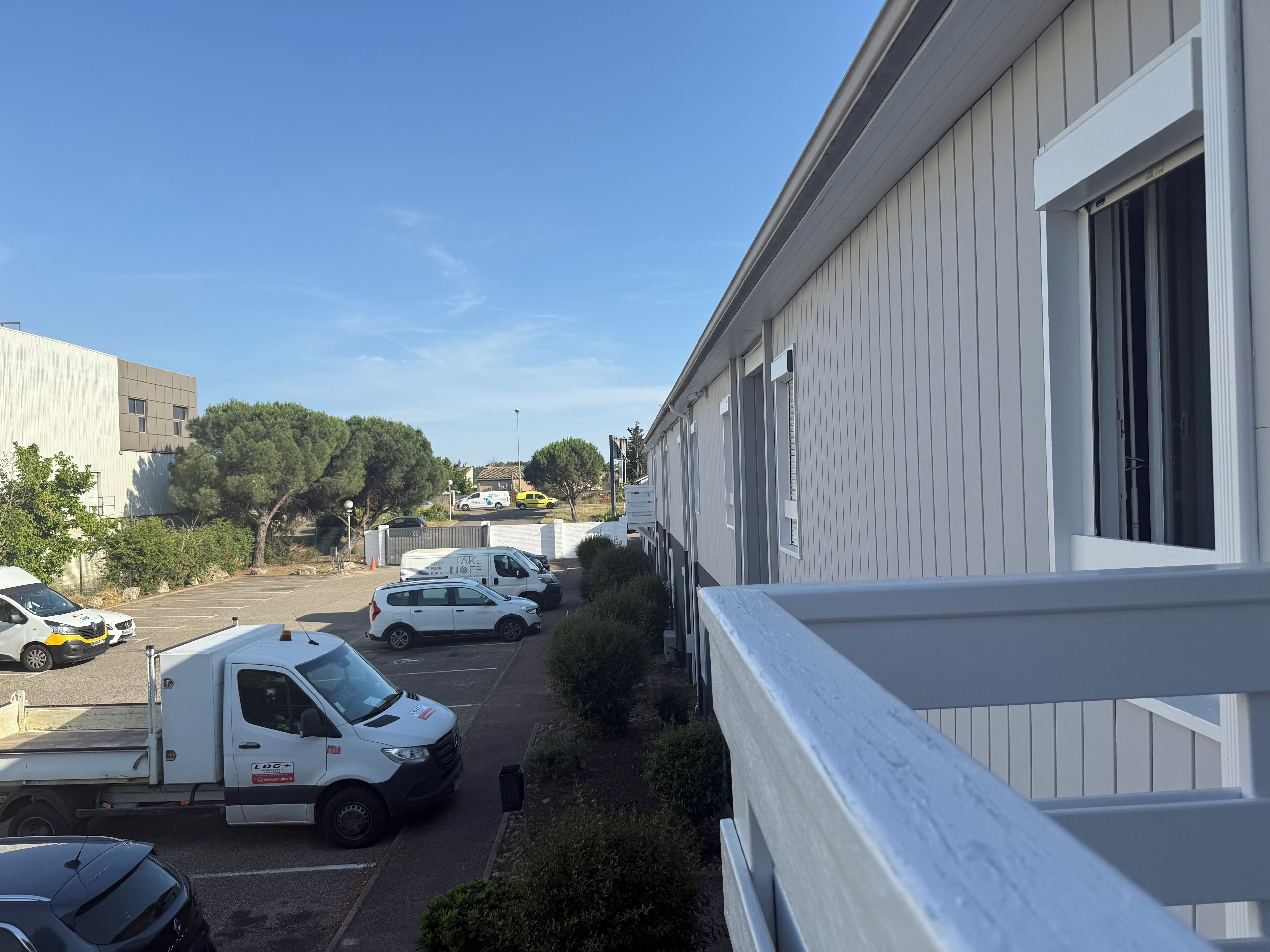 A parking area with several vehicles, including a white van and a black car.