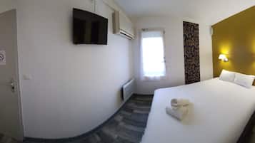 Habitación de hotel con cama, escritorio, teléfono, armario y televisor.
