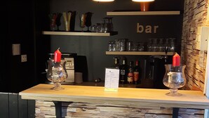 En bar med en bordplade i sten, hængende pendellamper og et træbord med et glasstage.