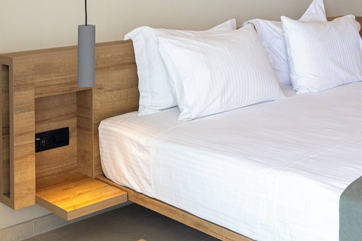 Un dormitorio moderno con cabecera de madera, estante empotrado y mesita de noche.