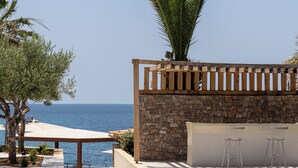 Un espace piscine agrémenté d’un mur en pierre, d’une pergola en bois et offrant une vue sur la mer.