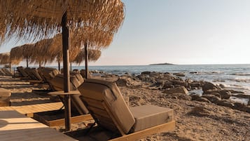 On the beach, black sand, sun loungers, beach umbrellas