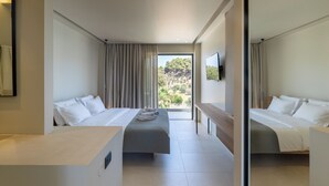 Une chambre d’hôtel moderne avec deux lits, une grande fenêtre avec des rideaux, un téléviseur à écran plat et un petit bureau.