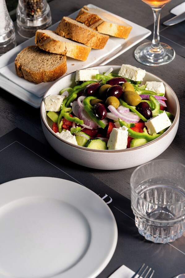 Ensalada con queso feta, aceitunas y verduras en un plato.