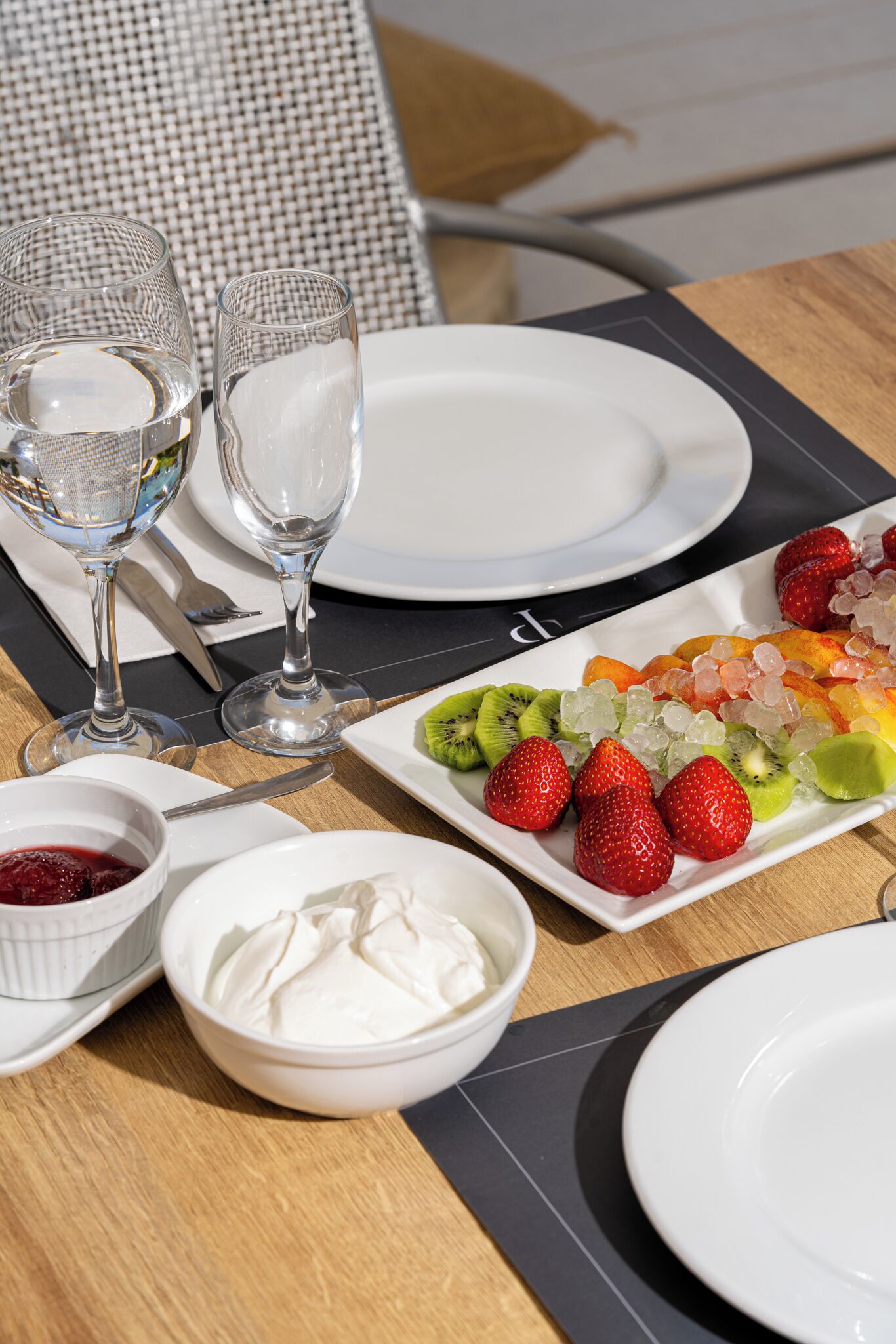 A table set for a meal with plates, glasses, and a fruit platter.
