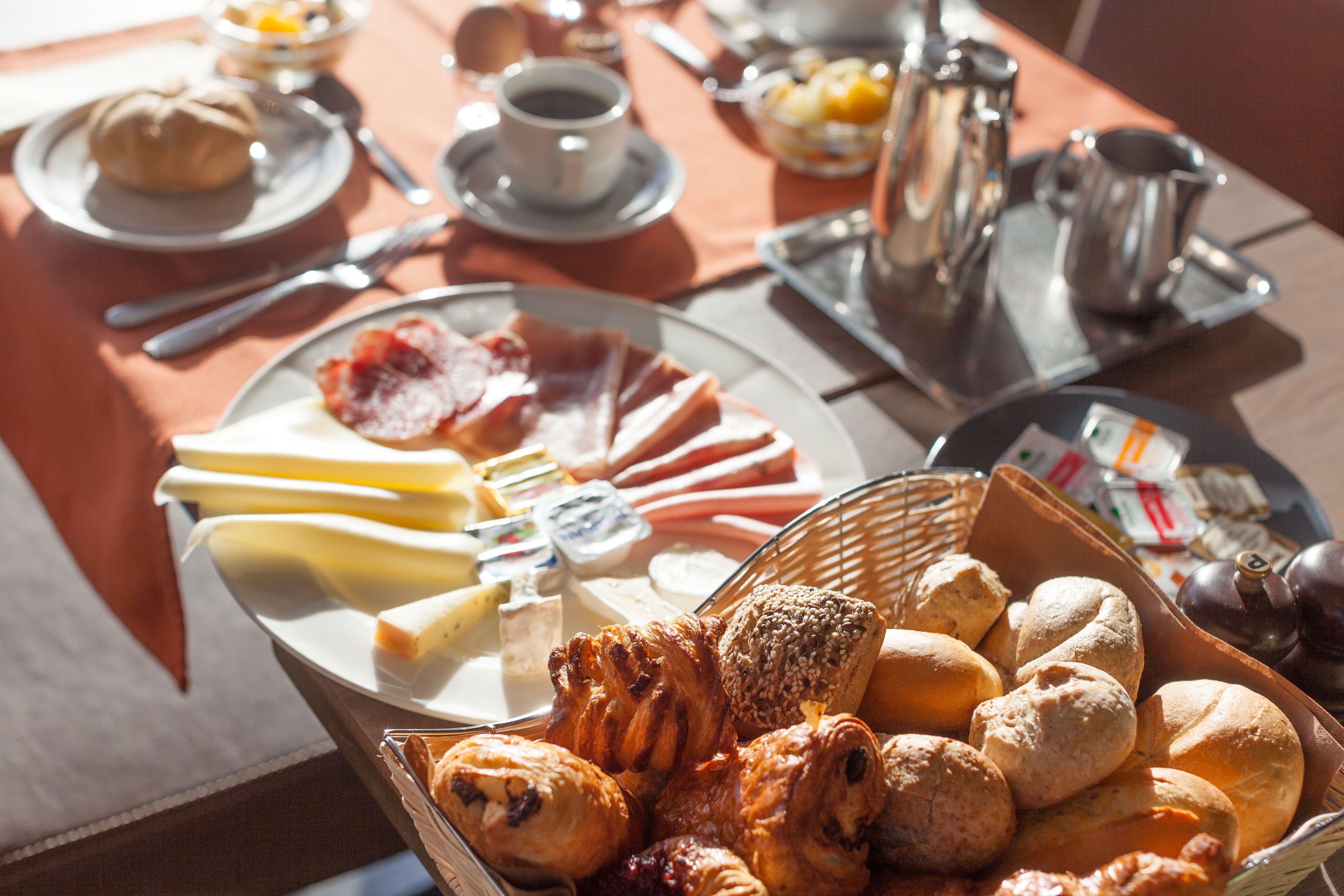 A breakfast buffet with various pastries, cheeses, and meats.
