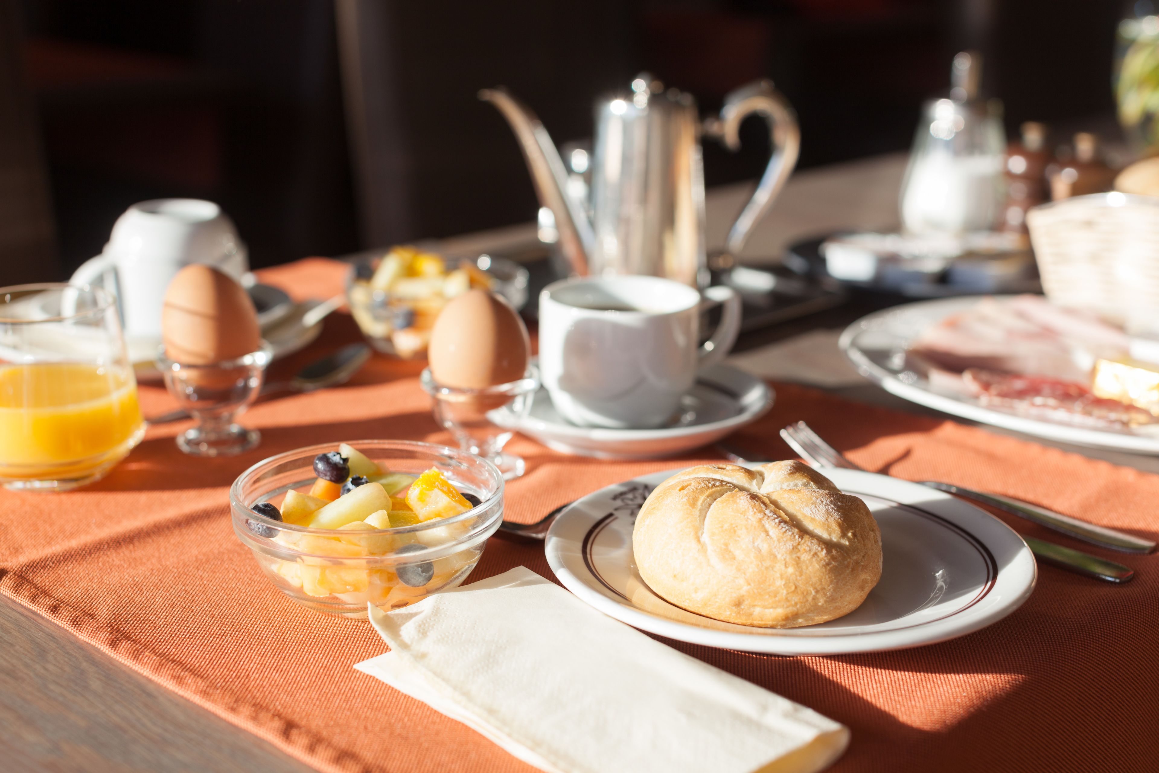 Une table de petit-déjeuner avec une variété d’aliments, notamment des œufs, des fruits et un croissant.