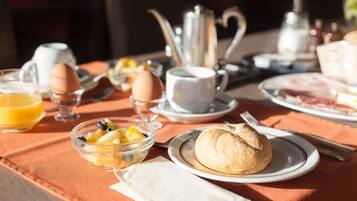 Une table de petit-déjeuner avec une variété d’aliments, notamment des œufs, des fruits et un croissant.