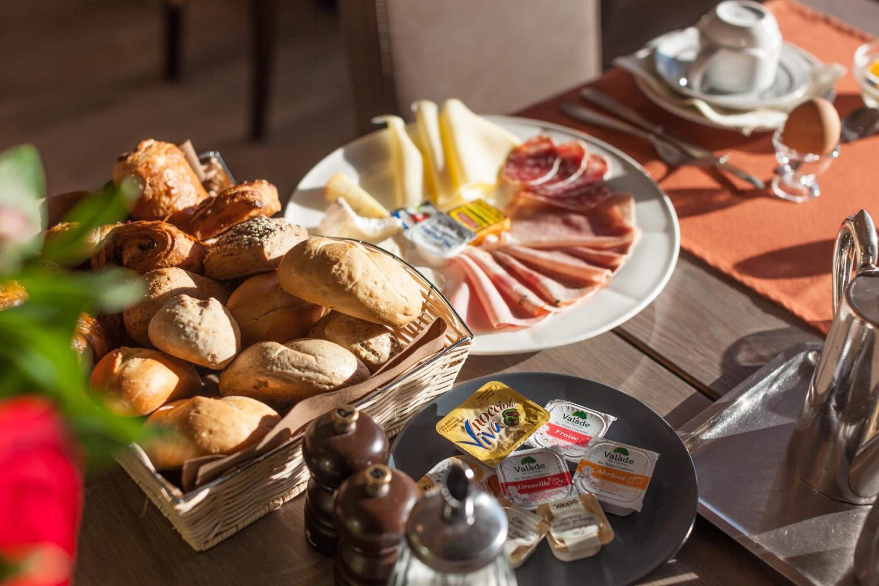 Un buffet de petit-déjeuner proposant un assortiment de pains, de viennoiseries, de fromages et de charcuteries.