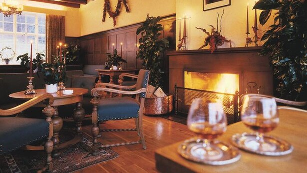 Una habitación acogedora con pisos de madera, una chimenea y una zona de estar con sofá y sillones.