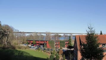 Un edificio de techo rojo con un estacionamiento y un puente al fondo.
