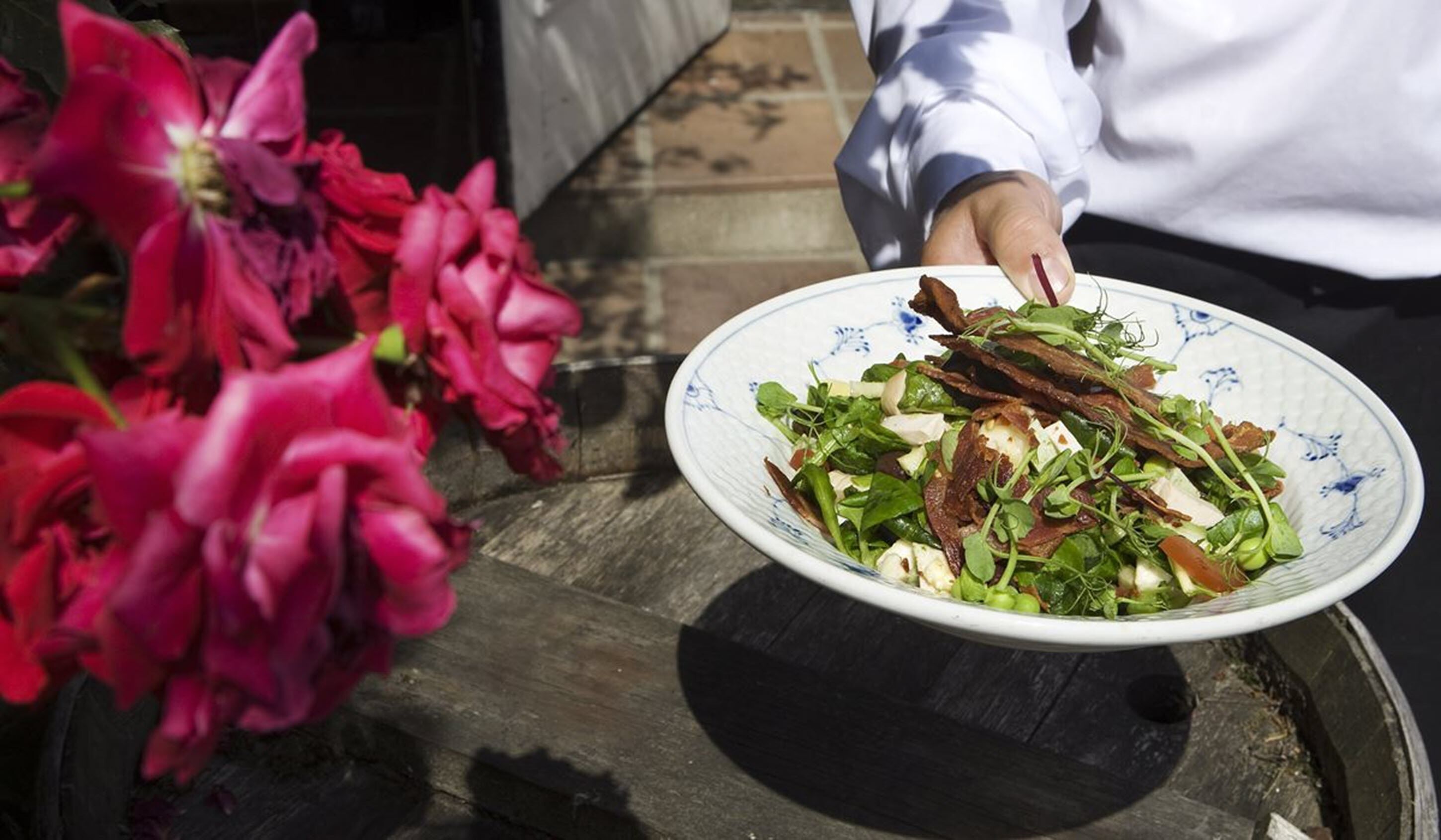 Una persona sosteniendo un plato de ensalada con diferentes verduras y ingredientes.