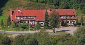 A two-story building with a red roof, multiple windows, and a flagpole with flags. - Sallingsund Færgekro (Nykobing Mors)