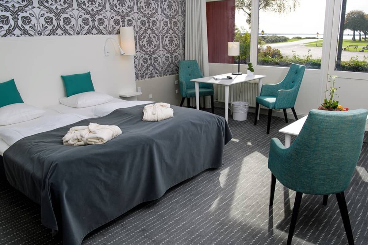 Une chambre d’hôtel avec un lit, deux chaises, une table et une vue sur l’extérieur.