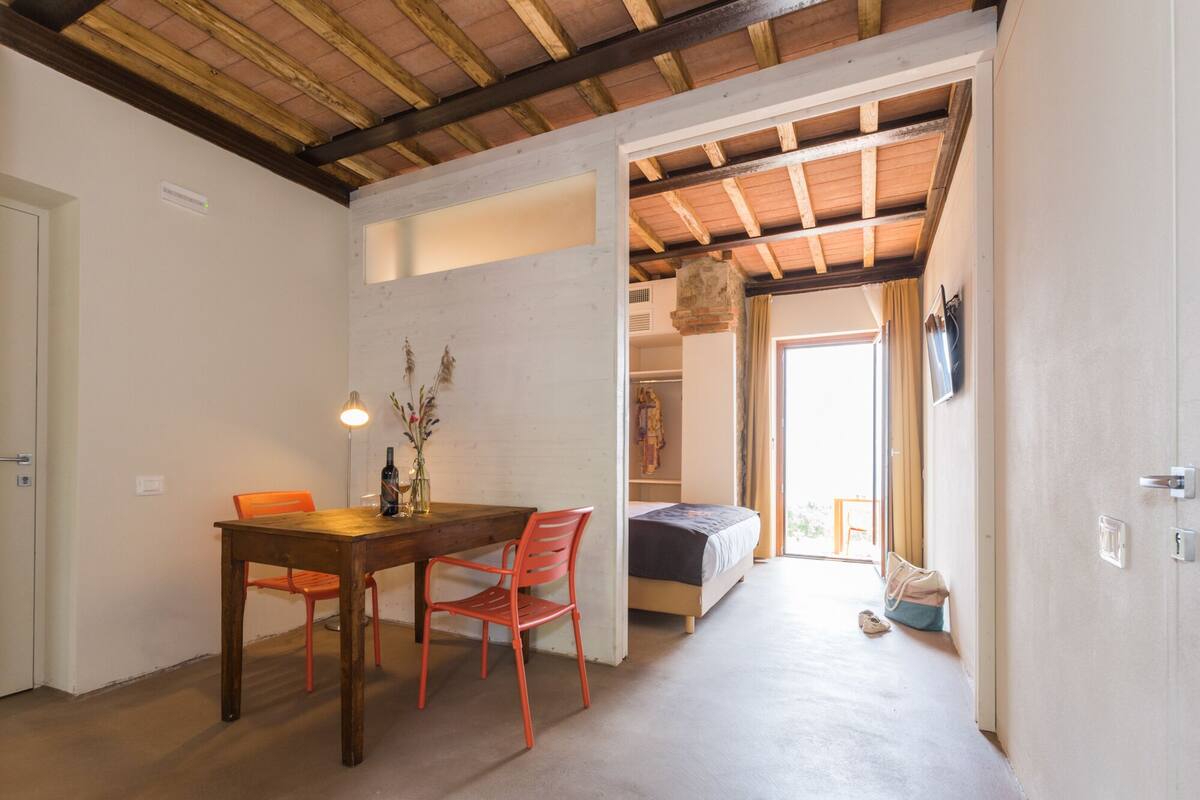 Una habitación con una mesa de comedor de madera, dos sillas, una cama y un armario.