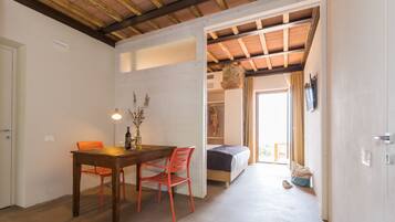 Una stanza con un tavolo da pranzo in legno, due sedie, un letto e un armadio.