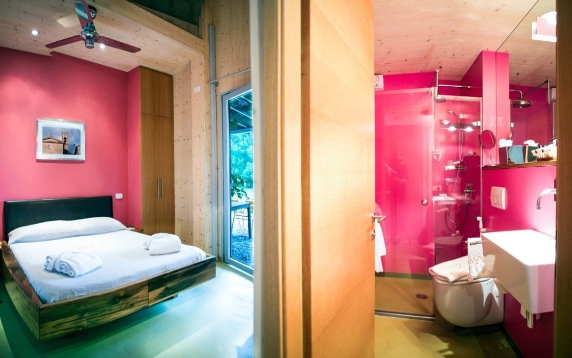 A bedroom with a bed, a window, and a bathroom with a sink and toilet.