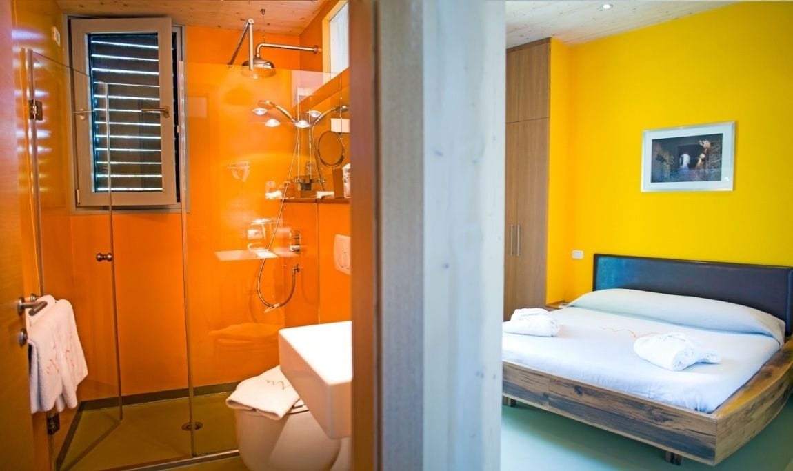 Quarto com chuveiro, cama, banheiro e um quadro na parede.
