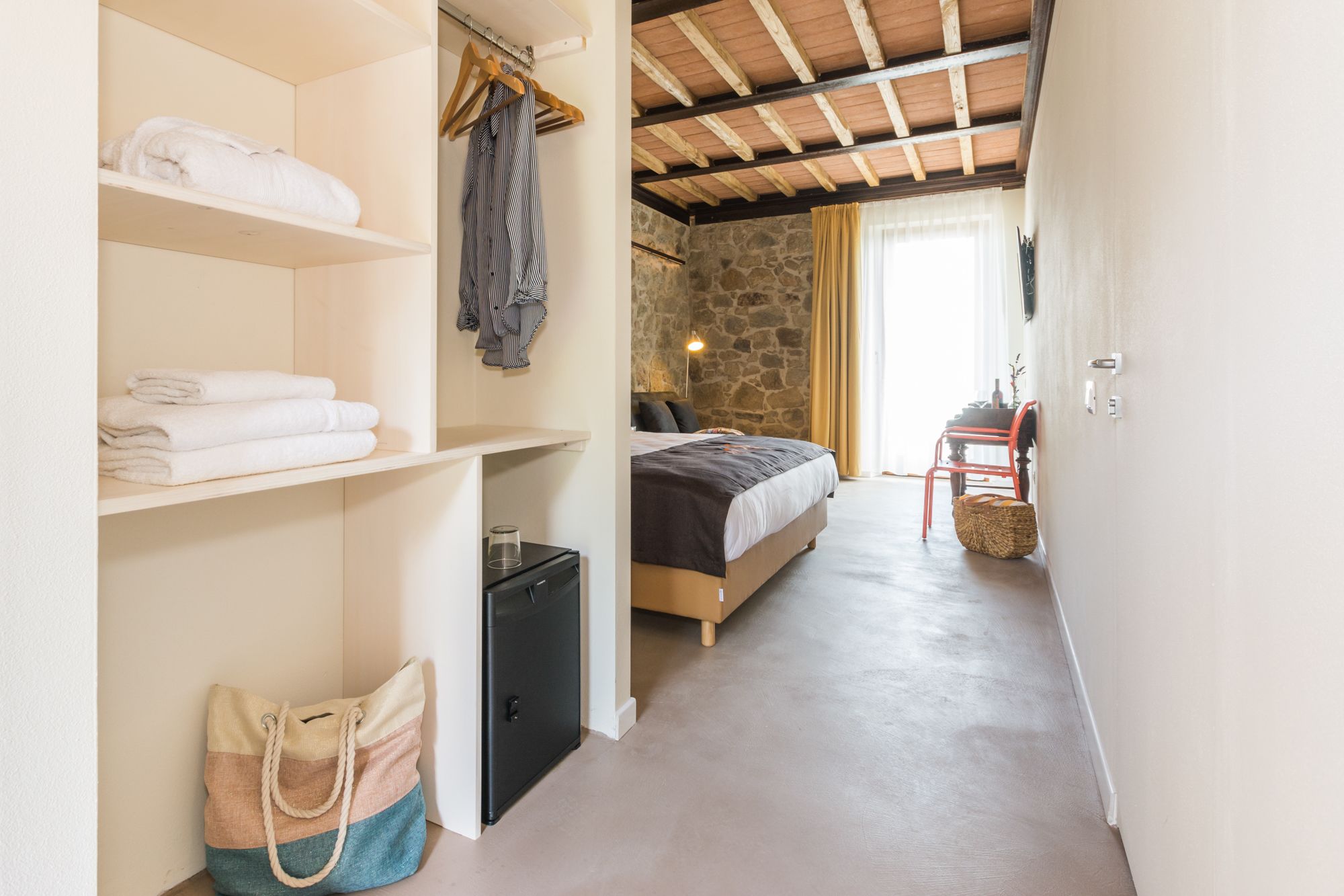 A bedroom with a bed, a wardrobe, a small table, and a chair.