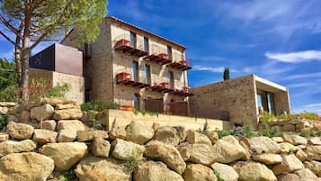 Situated on a rocky terrain, this two-story building features a balcony with a railing on the upper floor.