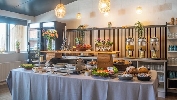 Een buffetopstelling met diverse etenswaren, een koffiehoek en decoratieve planten.