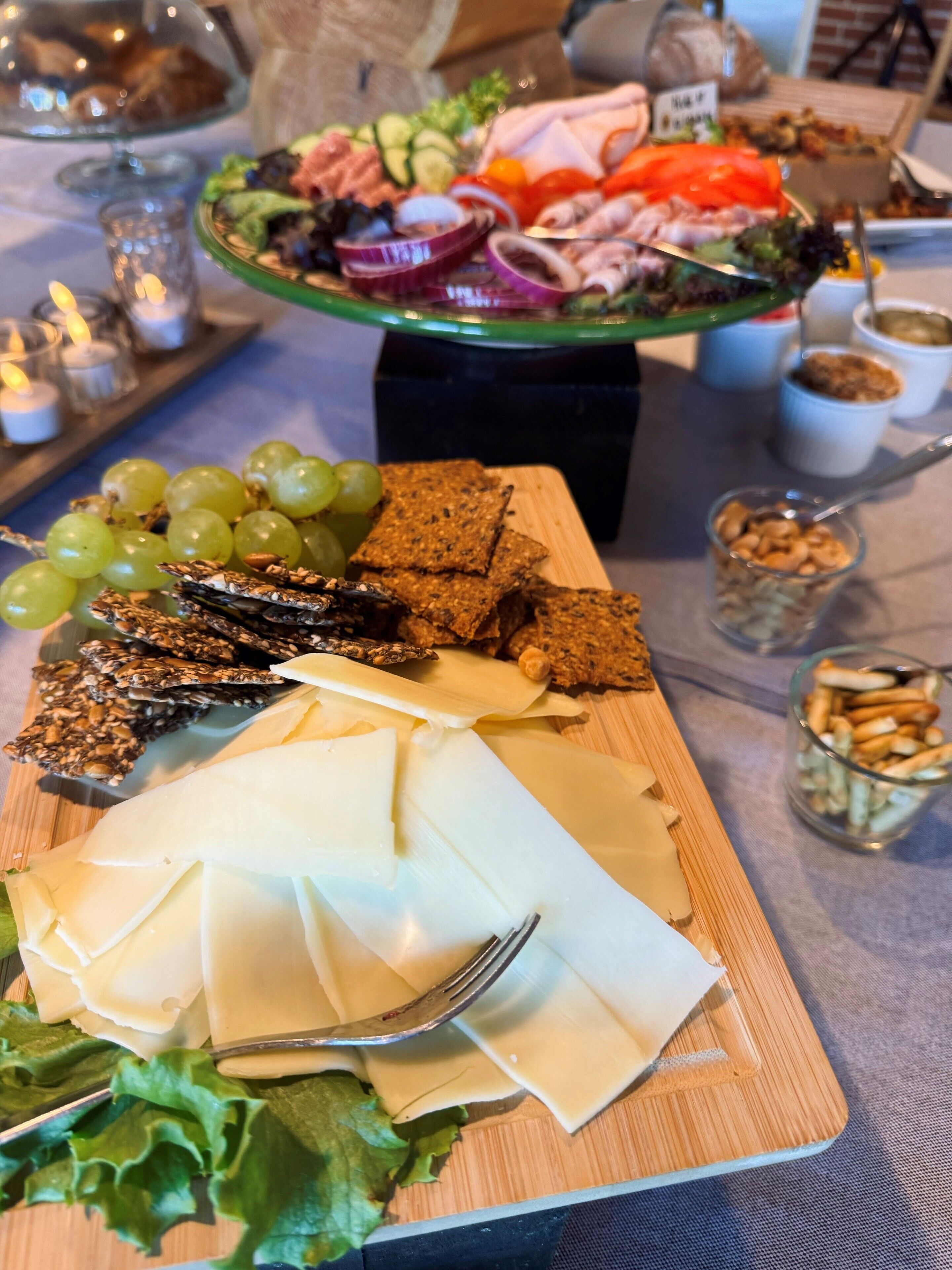A table with a variety of food items including cheese, crackers, grapes, and nuts.