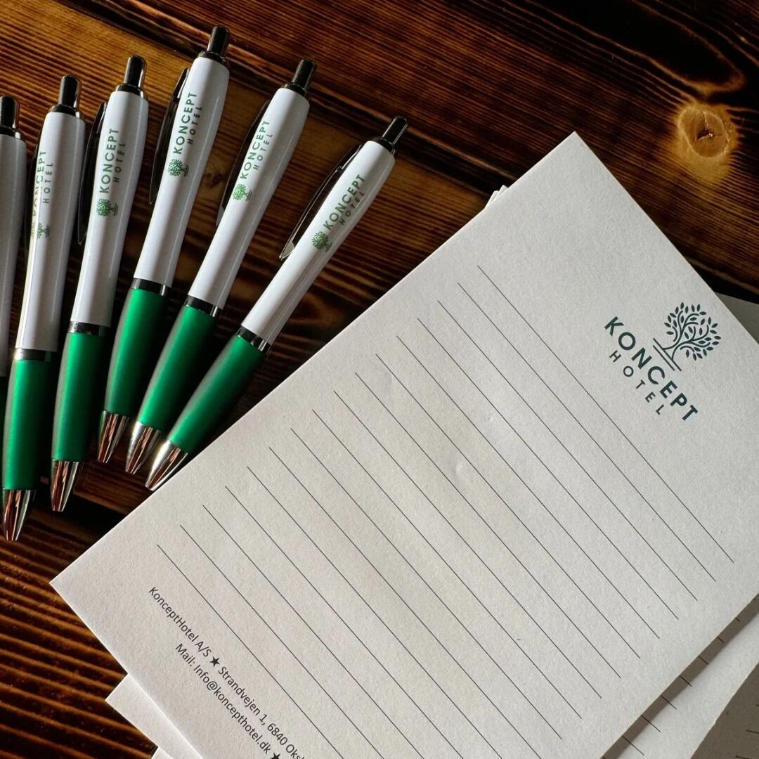 A hotel stationery set with pens and a notepad, featuring the hotel’s logo and contact information.