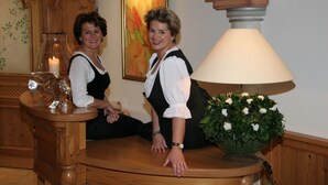 Two individuals seated at a wooden table with a lamp and a vase of flowers. - Hotel Landhaus Feckl (Ehningen)