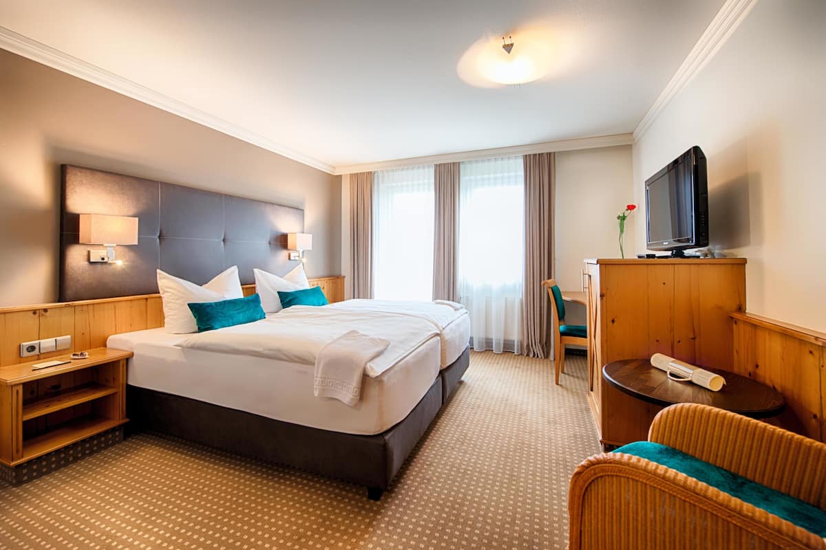 A hotel room with a large bed, a television, a desk, and a chair.
