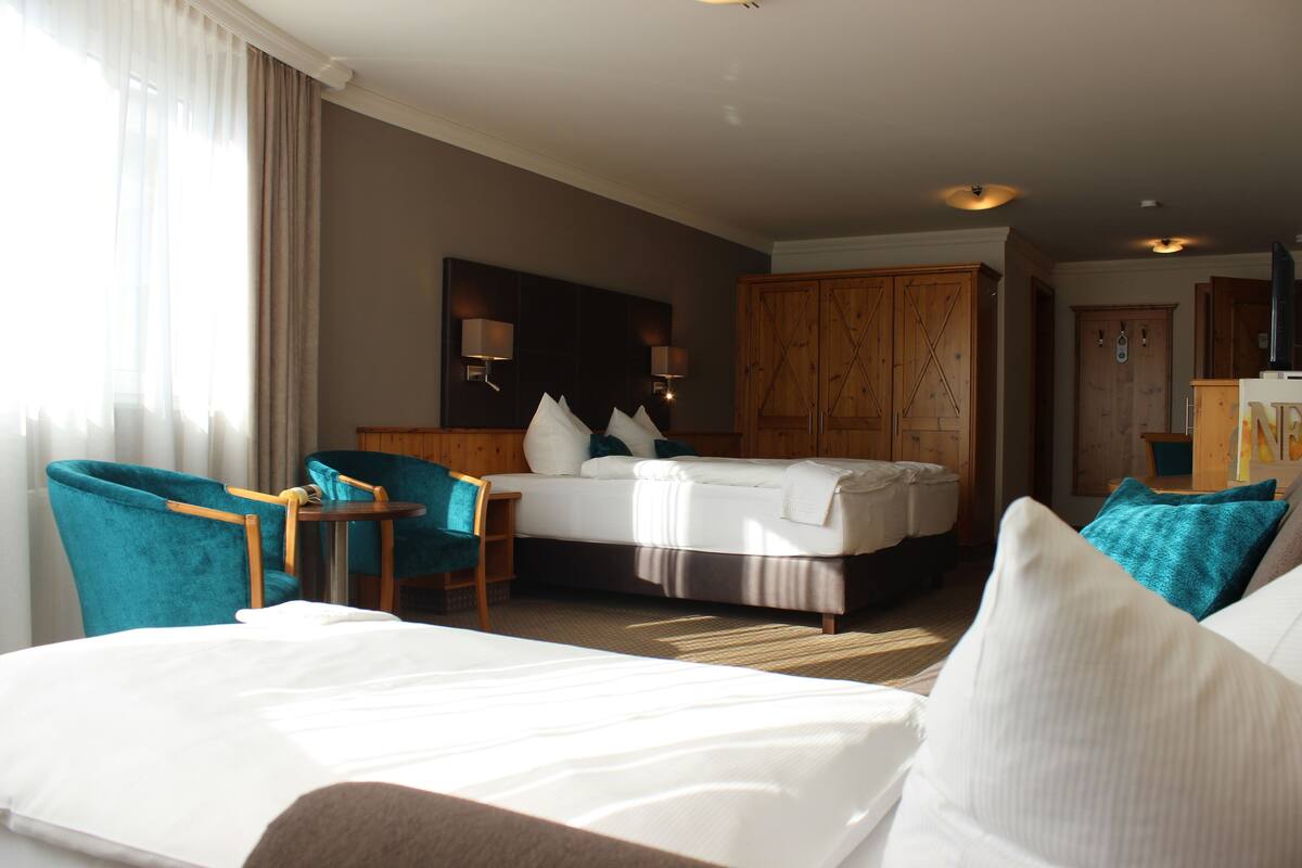A hotel room with a bed, two chairs, a desk, and a wardrobe.