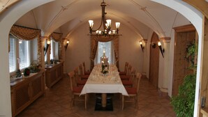 A dining area with a long table set for a meal, surrounded by chairs, under a high arched ceiling with a chandelier. - Hotel Landhaus Feckl (Ehningen)