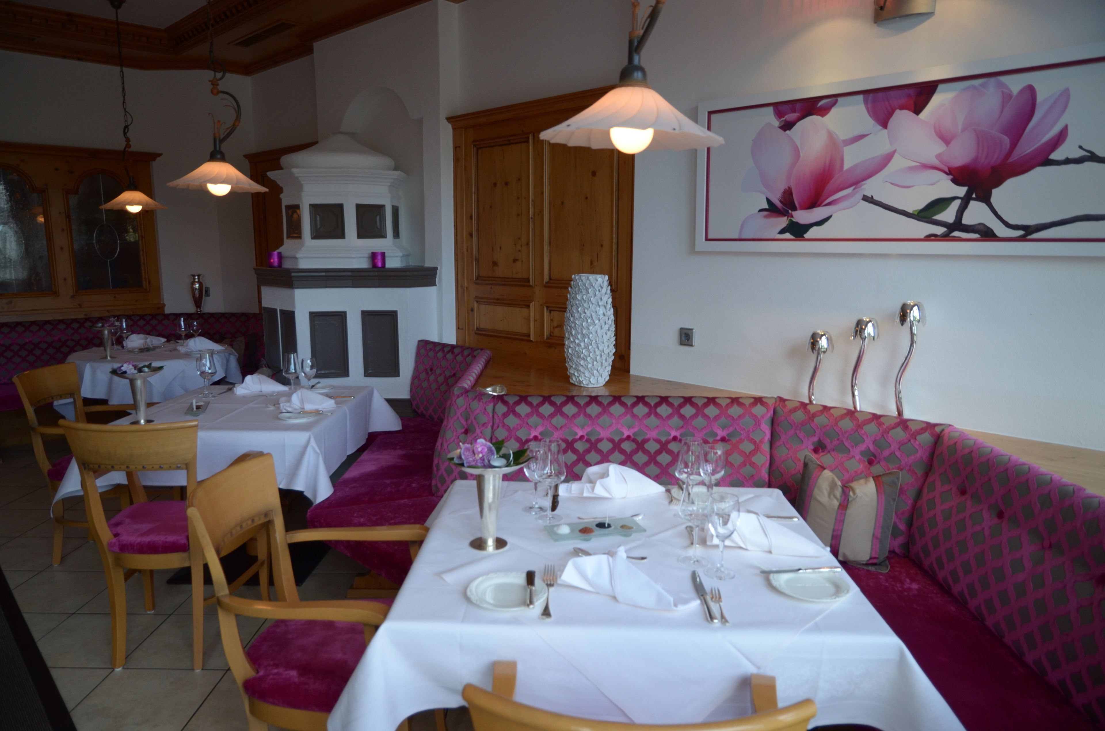 Un espace repas avec des tables dressées pour le repas, des chaises en bois et un banc rembourré.