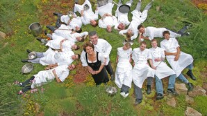 A group of people in white chef uniforms lying on grass with cooking utensils. - Hotel Landhaus Feckl (Ehningen)