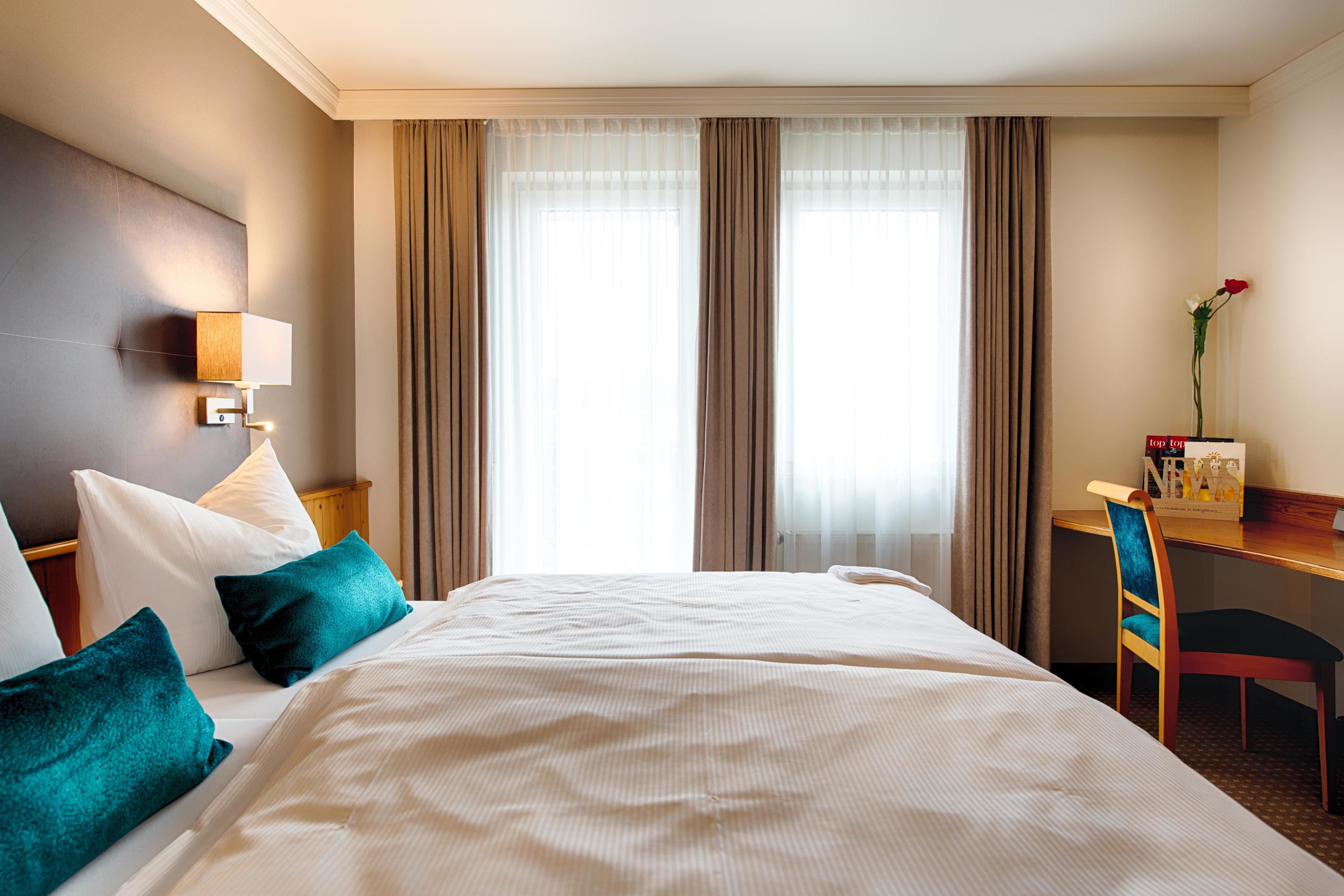 A hotel room with a large bed, a desk, and a chair.