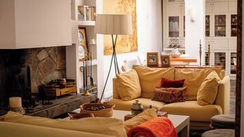 A cozy living room with a fireplace, a sofa, a coffee table, and a bookshelf.