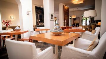 Een modern interieur met witte meubels, een centrale tafel met een decoratieve schaal, en een barretje op de achtergrond.