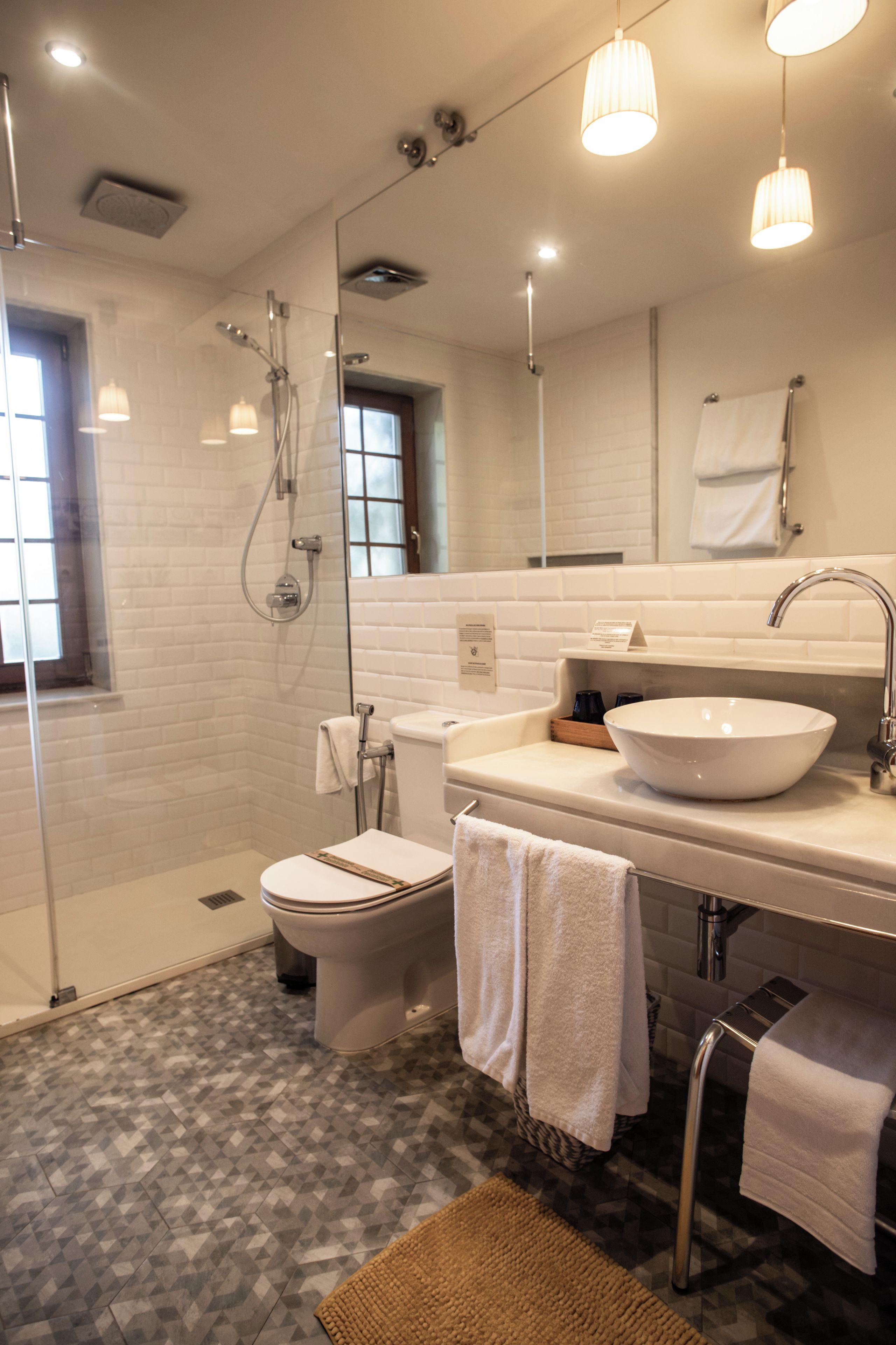 A modern bathroom with a glass-enclosed shower, a white toilet, a sink with a bowl, and a mirror above the mirror cabinet.
