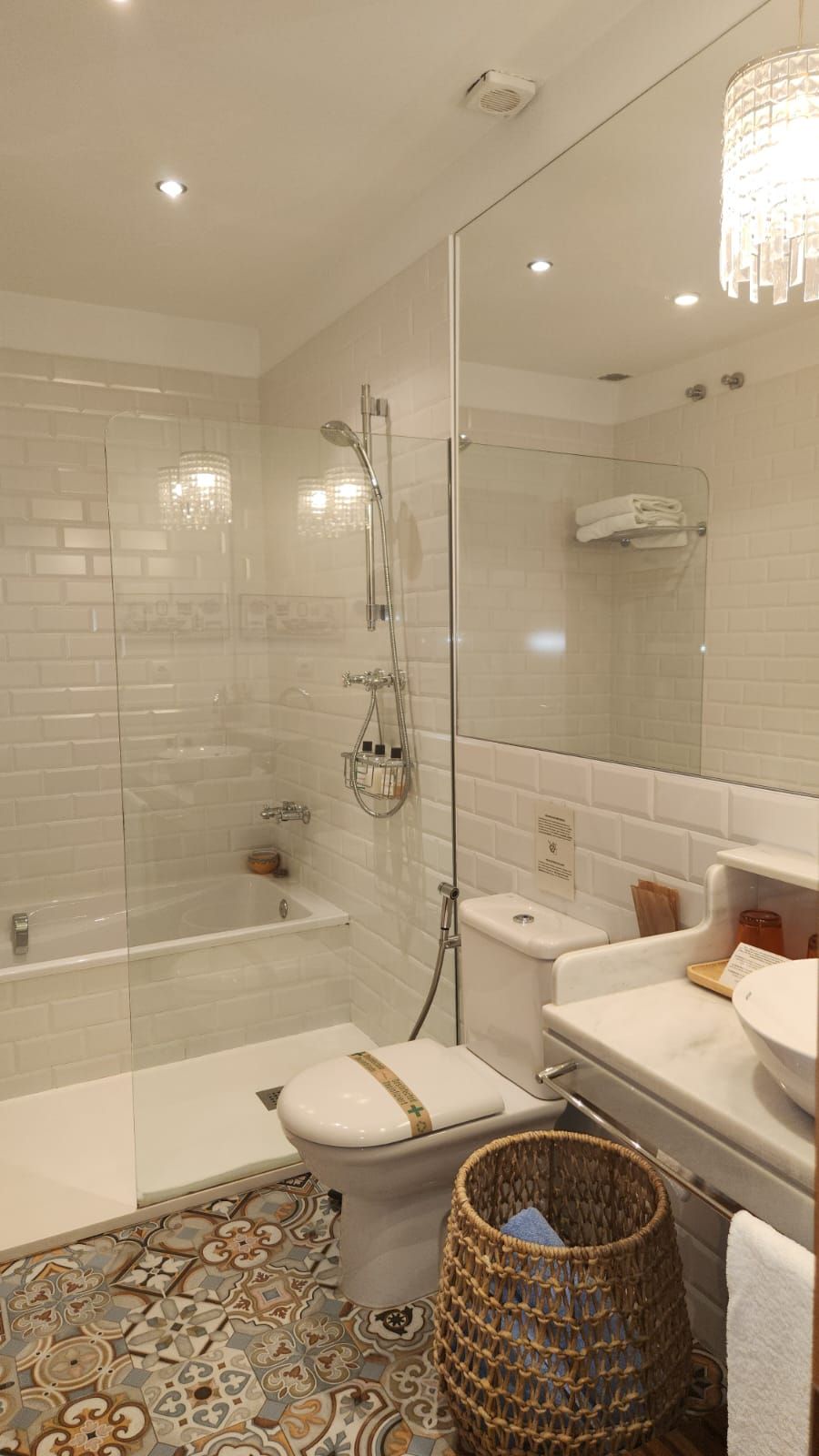 A modern bathroom with a glass-enclosed shower, a white toilet, a bathtub, and a vanity with a mirror.