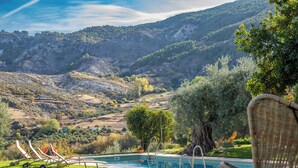 A pool with lounge chairs, a tree, and a mountainous landscape. - La Almunia del Valle (Monachil)
