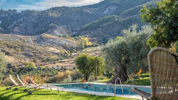 Una piscina al aire libre, sillones reclinables de piscina