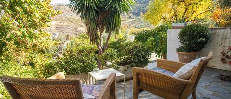 A patio with wicker furniture, a small table, and potted plants.