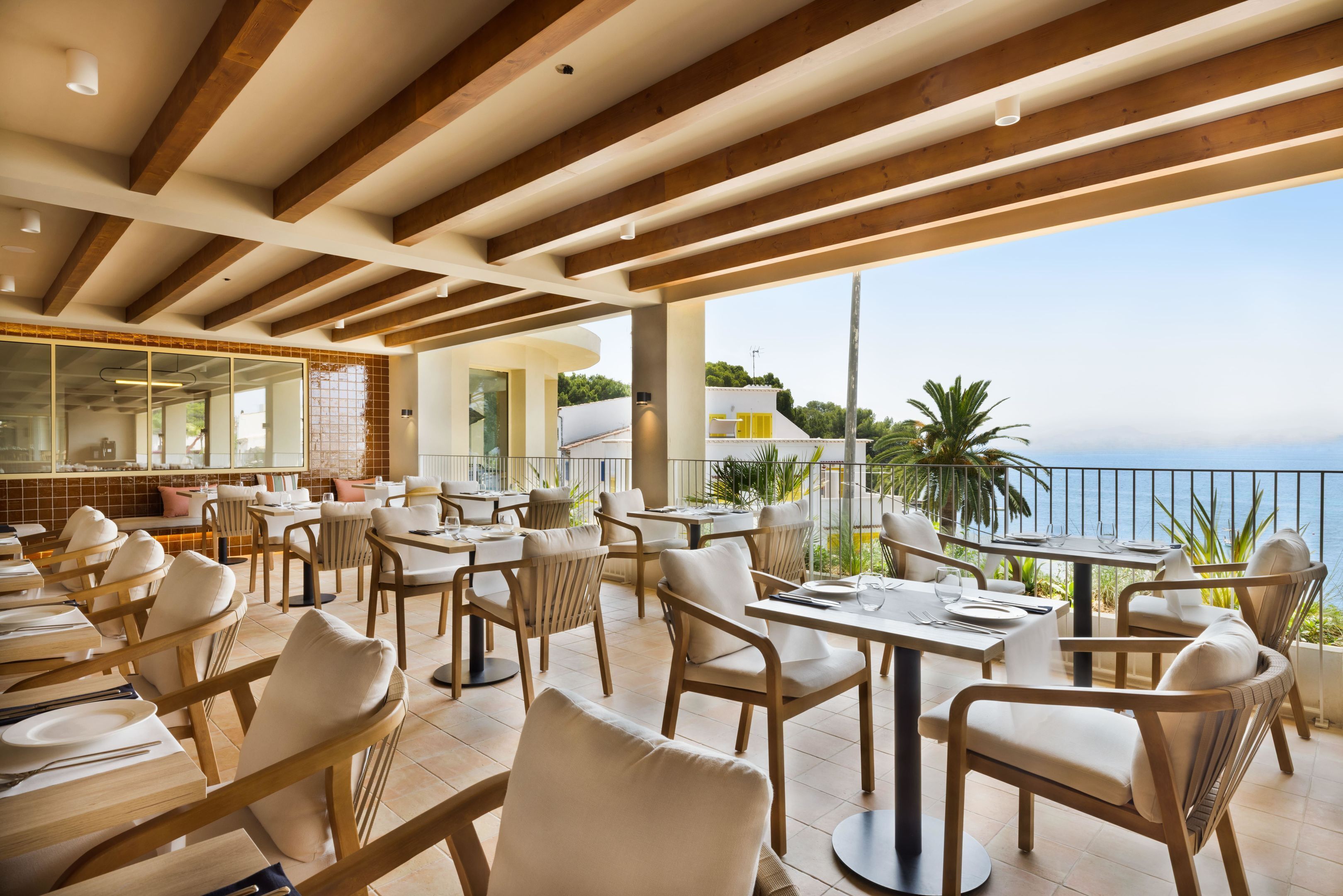 Un restaurante con terraza, vigas de madera y vista al mar.