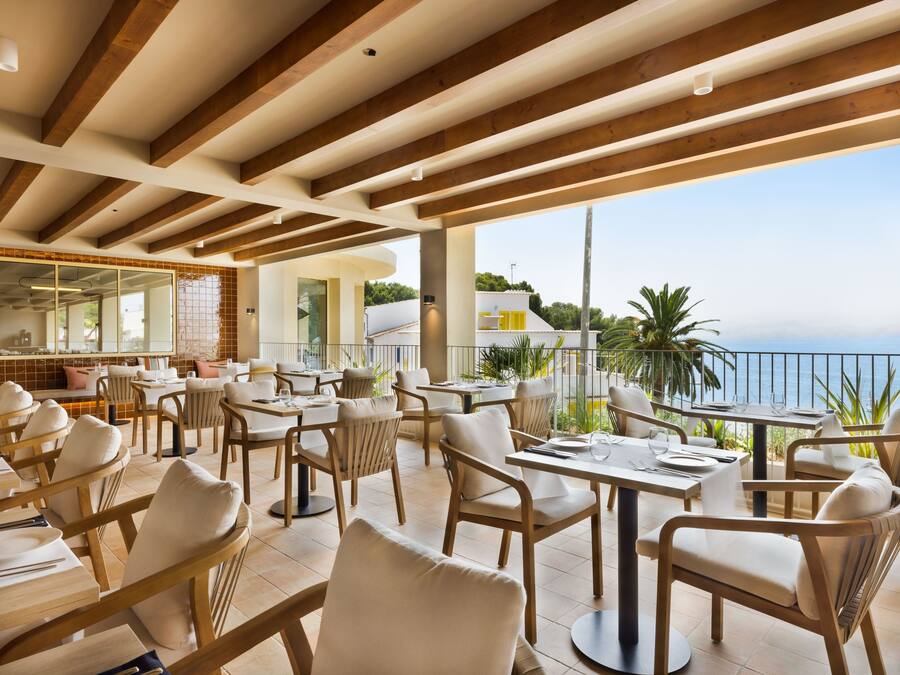 Un restaurante con terraza, vigas de madera y vista al mar.