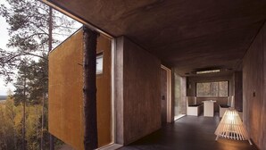 A modern interior with a wooden floor, a large window, and a seating area with a lamp. - Tree Hotel (Harads)